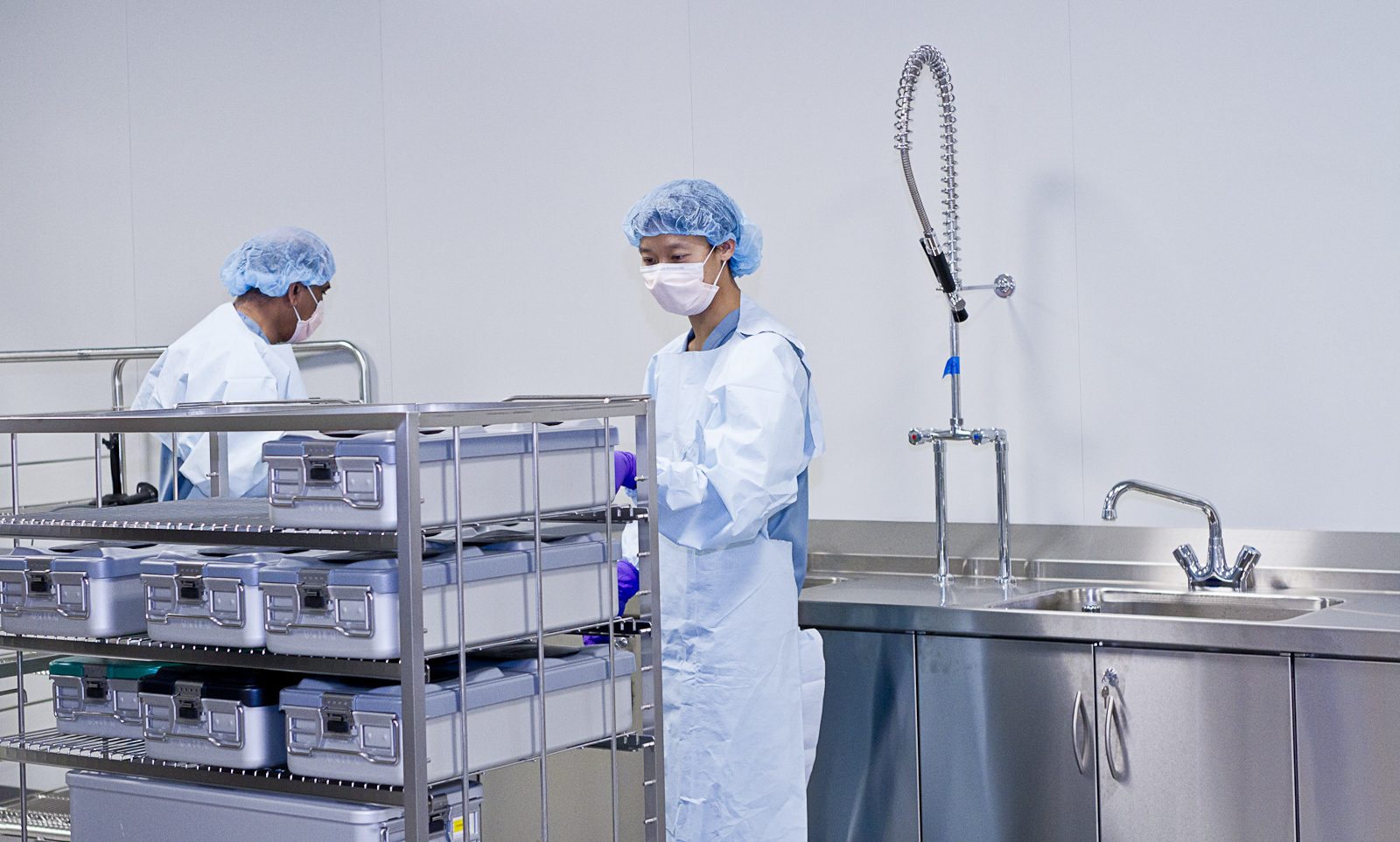 SteriPro technicians moving a cart of instrument containers through the centralized reprocessing facility