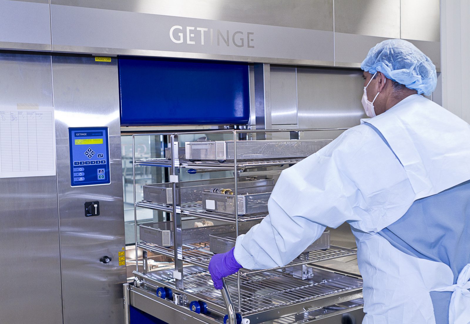 SteriPro technician loading instrument baskets into a Getinge steam sterilizer at the centralized facility